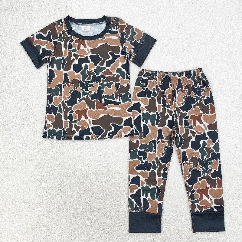 Green and brown camouflage toddler pajama set with short sleeves and black cuffed pants, laid flat on a white surface